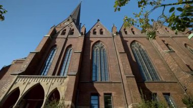 HAMBURG, Almanya - 23 Eylül 2024: Gotik St. Peter Kilisesi yüksek kemerli pencereler ve açık gökyüzü altında tuğla cephe. Eski şehrin alçak açılı çekimlerinde tarihi Hristiyan mimari yapıları inşa ediliyor.