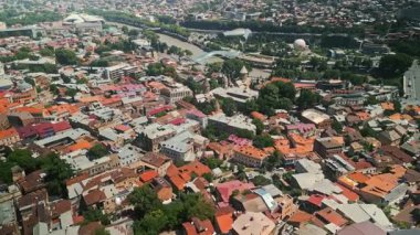 TBILISI, GEORGIA - 17 Haziran 2024: Tiflis, Georgia 'daki renkli çatıların ve tarihi kiliselerin panoramik insansız hava aracı görüntüleri. Barış Köprüsü ve Kura Nehri görünür, kentsel ve kültürel güzelliği yakalıyor