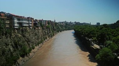 TBILISI, GEORGIA - 17 Haziran 2024: Tiflis 'teki Kura Nehri' nin üzerindeki kayalıklara tünemiş eski geleneksel Gürcü evlerinin manzarası.