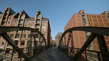 HAMBURG, Almanya - 23 Eylül 2024: Güzel bir günde Speicherstadt ilçesini kanal üzerinde yaylı eski köprü birbirine bağlar. Gökyüzünün altında endüstriyel bloktan viyadük ve çok katlı binalar