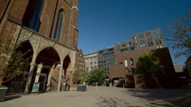 HAMBURG, ALMANY - 23 Eylül 2024: güneşli caddedeki yeniden tasarlanmış deponun yanındaki cephede dekoratif kemerli eski tuğla bina. Avrupa şehrinin tarihi caddesinde yürüyorum. Seyahat tatili