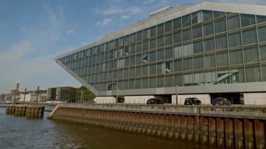 HAMBURG, Almanya - 23 Eylül 2024: Altona Altstadt bölgesindeki Elbe nehir kıyısında düzensiz geometrik şekilli liman ofis binası. Güneşli bir günde endüstriyel limanda modern mimari yapı