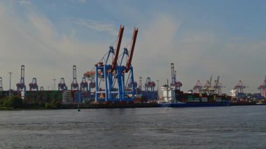 HAMBURG, GERMANY - 23 Eylül 2024: Elbe Nehri üzerindeki şehir limanında uzun vinçleri olan konteynır vinçleri. Limandaki modern tersanede güzel bir günde nakliye ekipmanları. Gemiler için deniz kompleksi