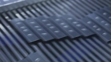 Bulanık siyah endüstriyel parçalar otomatikleştirilmiş üretim hattındaki yüksek hızlı taşıma bandında hareket ediyor, fabrikada hareket halinde olan hassas üretimi gösteriyor.