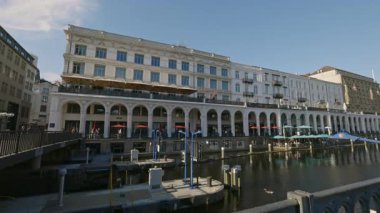 HAMBURG, ALMANY - 23 Eylül 2024: Nehir kıyısındaki pazar yeri ön cephesinde tarihi Alster Çarşıları. Mavi gökyüzünün altında şehir seti üzerinde restoran terası olan popüler halk merkezi.