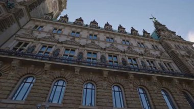 HAMBURG, Almanya - 23 Eylül 2024: mavi gökyüzüne karşı tarihi belediye binasının zarif cephesinde parlak pencereler. Şehir merkezinde nefes kesen baş idari yapı mimarisi