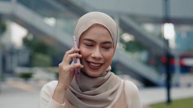 İş kadını tesettürlü tesettür resimleri şehir merkezinde akıllı telefon yürüyüşlerinde konuşuluyor. Başörtülü Malezyalı kadın şehir merkezinde mobil iletişimde güven yayıyor