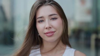 Çekici bir genç kadının portresi. Şehirli bulanık arka planda duran cilveli gülüşler. Gevşek saçlı güzel bir kadın yaz şehri ortamında olumlu duygular ifade eder. Doğal güzellik.
