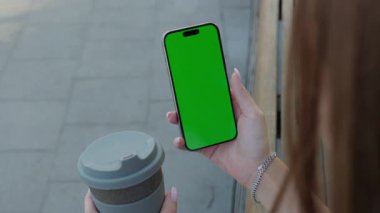 Kadın elleri, şehirde akıllı telefonları maket ekranı ve kahve fincanı ile tutuyor. Kadın cep telefonunda mobil uygulama kullanıyor ve sokak ekinlerini boş gösteriyor. Tasarım şablonu