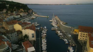 Liman, dar rıhtımda demirli teknelerle parıldıyor. Marina, dalgakıranlarla kayıklar sallanırken, Adriyatik Denizi 'ne doğru uzanan rıhtım ve kıvrımlar olarak görünümü emrediyor