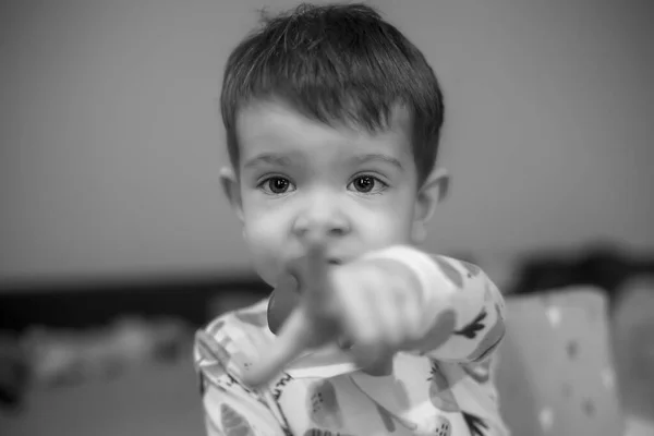 Siyah beyaz bir çocuk portresi. Önündeki bir şeyi işaret ediyor.