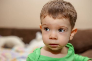 Bir çocuğun portresi oturuyor ve uzaklarda bir yerlere bakıyor.