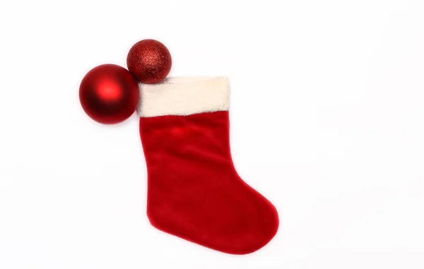 Kırmızı Noel çorapları ve beyaz arka planda iki kırmızı Noel topu.