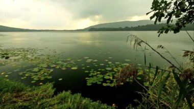 Yağmurlu bir günde gölün üzerinde gün batımı