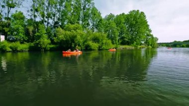 Göl, ağaçlar ve kanolarla kaplı manzara