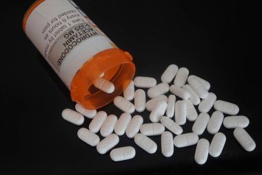 Reçeteli şişeden siyah arka plana dökülen opioid ağrı kesicileri kapatın.