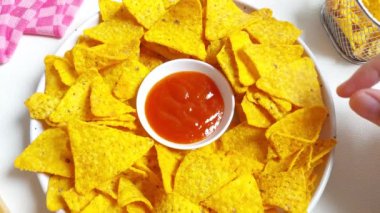 Kadın eli beyaz tabakta Nachos tortilla mısır cipsi alıyor. İzole edilmiş arkaplan beyaz
