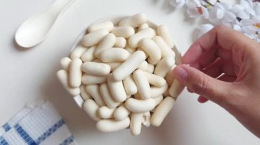 Kadın eli Pilus Keju alır. Endonezya 'dan gevrek bir atıştırmalık. Beyaz kasede servis edilmiş. İzole edilmiş arkaplan beyaz.