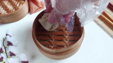 Kadın eli bambu buharlı tencereye çiğ mantı ya da gamsum koyar. Geleneksel Çin yemekleri. Tadı tuzlu.