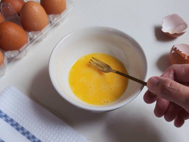 Yemek hazırlama fotoğrafçılık konsepti. Beyaz kasede yumurta çırpmak. İzole edilmiş arkaplan beyaz.