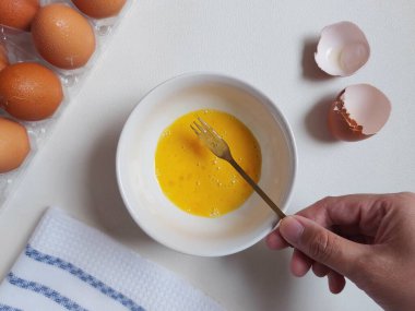 Yemek hazırlama fotoğrafçılık konsepti. Beyaz kasede yumurta çırpmak. İzole edilmiş arkaplan beyaz.