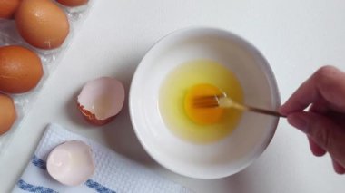 Beyaz kasede yumurta çırpmak. Beyazlar içinde izole edilmiş bir arka plan. yemek hazırlama video konsepti.  