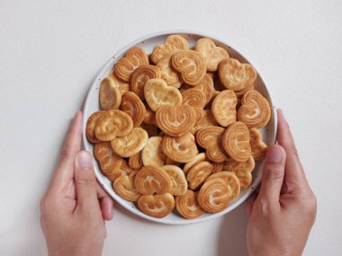  Kalp şeklinde şeker serpiştirilmiş bisküviler beyaz tabakta. İzole edilmiş arkaplan beyaz.