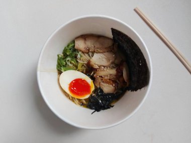 Chicken ramen noodle on paper bowl. It is authentic food from japan. Usually consist of noodle, soup, boiled egg, spring onion, seaweed, chicken meat. Completed with chopsticks. Savory taste