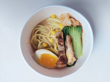 Ramen noodle on paper bowl. Completed with boileg egg,vegetable,chicken grilled, swert corn and soup. It is japanese traditional food