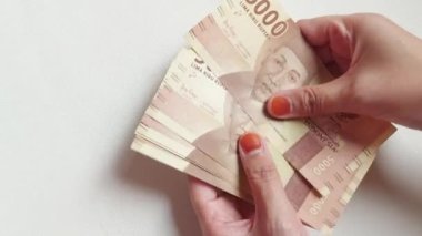 Woman hand counting Five thousand rupiahs. Indonesian money. Isolated background in white.