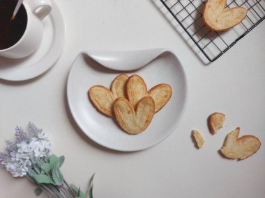 Orijinal turta bisküvileri ya da poğaça, fil kulağı ya da Fransız kalbi kurabiyesi ya da poğaça, bal, çift fırıldak ya da kelebek kurabiyelerinden yapılmış palmier bisküvi. Beyaz tabakta servis edilir..