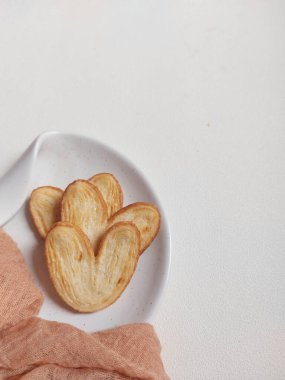 Orijinal turta bisküvileri ya da poğaça, fil kulağı ya da Fransız kalbi kurabiyesi ya da poğaça, bal, çift fırıldak ya da kelebek kurabiyelerinden yapılmış palmier bisküvi. Beyaz tabakta servis edilir..