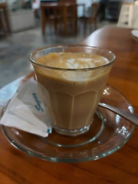 A cup of coffee with latte art. Comoleted with plate, spoon and sugar