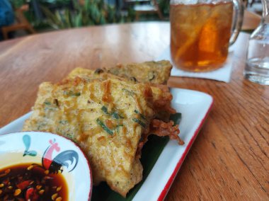 Tempe mendoan. It is traditional food from Indonesia. Made from fried tempeh which wrapped with flourm served with sweet soy sauce. clipart
