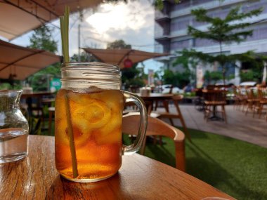 A glass of ice tea with lemongrass on the wooden table. With blurred of cafeteria view