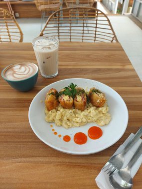 Peynirli makarna ve füme sığır eti. Beyaz tabakta servis ediliyor. Acı biber sosu ve kereviz ile süslenmiş. Kremalı ve tuzlu