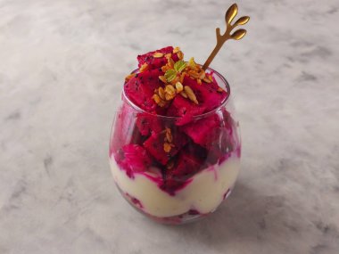 ejderha meyveli parfe. Sağlıklı bir yiyecek. Granola, yoğurt, dargon meyvesi ve nane yapraklarıyla süslenmiş.. 
