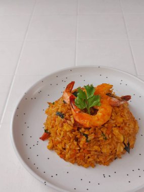 Kızarmış karides pilavı. Pirinç, karides, yumurta, havuç, susam yağı, margarin, ançüez, taze soğan, soya sosu, domates sosu, istiridye sosu, mantar çeşnisi. Kerevizle süslenmiş.. 