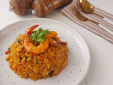 Kızarmış karides pilavı. Pirinç, karides, yumurta, havuç, susam yağı, margarin, ançüez, taze soğan, soya sosu, domates sosu, istiridye sosu, mantar çeşnisi. Kerevizle süslenmiş.. 