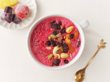 Bir kase karışık meyve püresi. Pancar, ananas ve çilek suyundan yapılmış. Kurutulmuş meyve ve fındıkla kaplı. Sağlıklı gıda konsepti. İzole edilmiş arkaplan beyaz