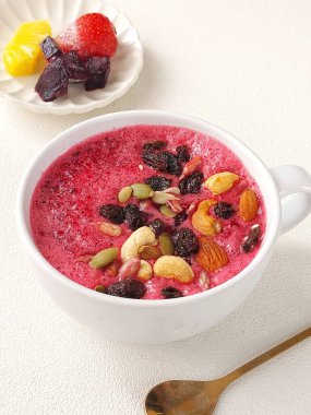 Bir kase karışık meyve püresi. Pancar, ananas ve çilek suyundan yapılmış. Kurutulmuş meyve ve fındıkla kaplı. Sağlıklı gıda konsepti. İzole edilmiş arkaplan beyaz