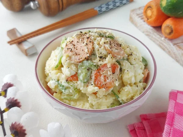 Japon patates salatası. Sirke, mayonez, haşlanmış yumurta, tuz, salatalık, havuç, sosis ve karabiberden yapılmış patates püresi. Kasede servis edilmiş. Geleneksel Japon yemekleri.. 