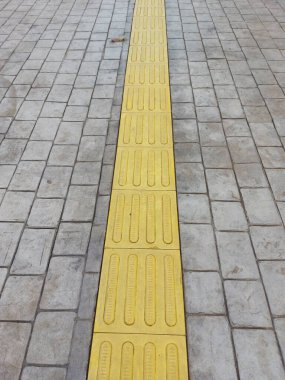 Körler için kaldırım rehberleri. Körler için kaldırımdaki sarı beton kaldırım taşları. Körler için yol