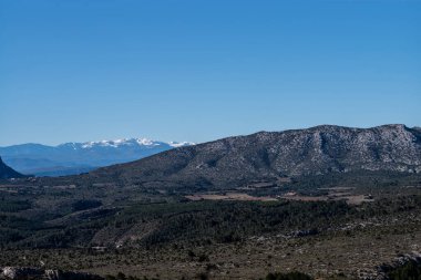Bulutlu gökyüzünün altında yüksek açılı bir dağ sırası.