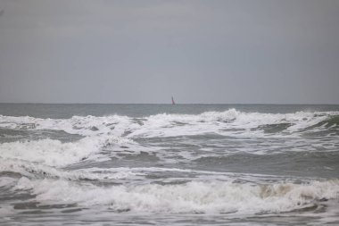 Büyük fırtına dalgaları ve bulutlu gökyüzü olan bir deniz manzarası..