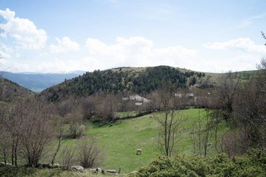 İtalya 'da bir dağ manzarasında bir evin önündeki yeşil çimenler ve ağaçlar.