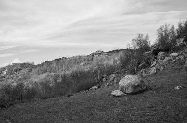 Arkasında beyaz bulutlar olan kayalık tepelerin güzel bir görüntüsü.