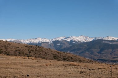Karlı, güzel kış manzarası. Kaplanmış dağlar ve mavi bir gökyüzü.