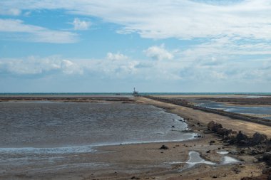 Büyük beyaz bir deniz feneri ve büyük bir denizi olan güzel bir deniz manzarası.