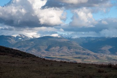Dağlar karla kaplı ve mavi gökyüzü kışın beyaz bulutlarla